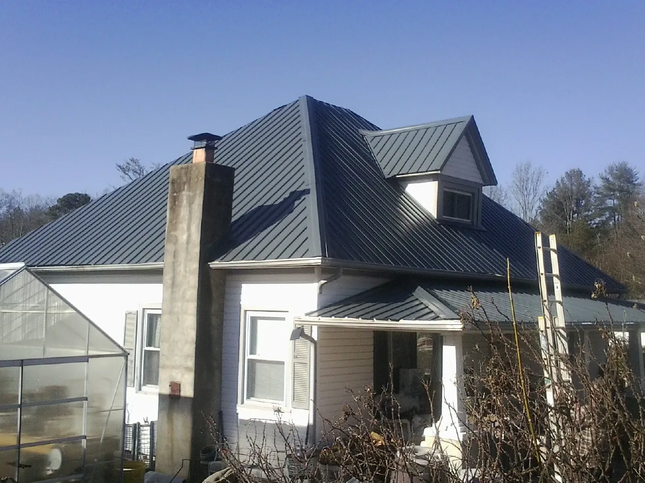 Dark blue standing seam metal roof on a white farmhouse with dormer — Slate & Tile Roof Repair by Roofing Brothers in Dixon