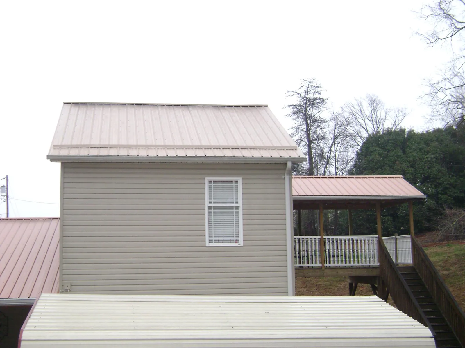 Tan metal roofs on a two story addition and attached porch, from a Roof Replacement job in Dixon
